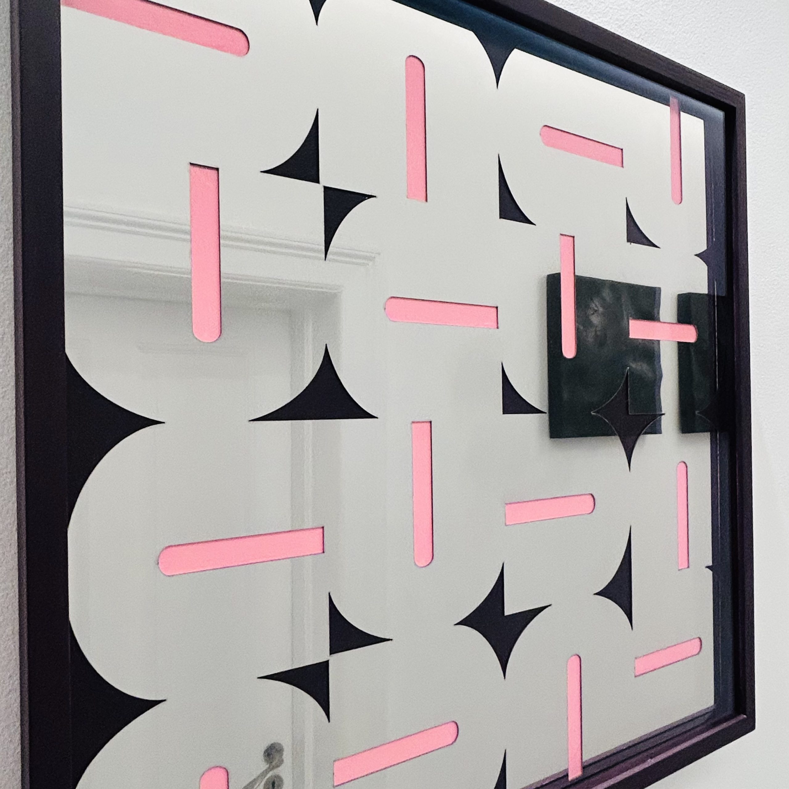 Naerbillede af et spejlpoleret U-relief med lyseroede fluorescerende streger, der spejler rummet omkring sig