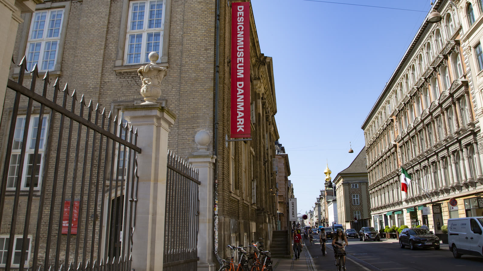 Facaden paa Designmuseum Danmark i Bredgade med det roede banner, set mod Marmorkirkens gyldne kuppel