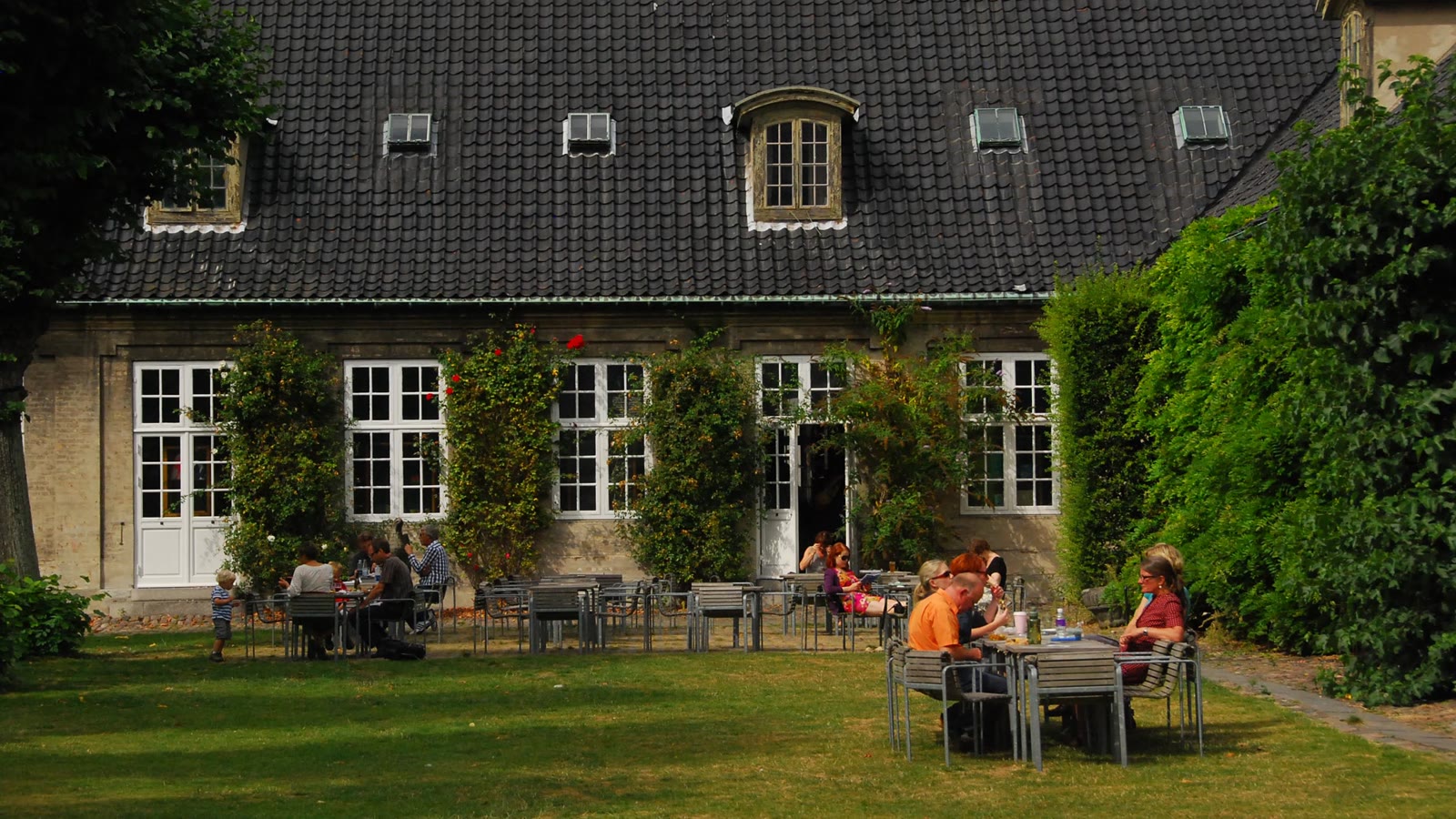 Museumshaven paa Designmuseum Danmark med cafeens borde paa graesplaenen foran den gamle hospitalsbygning